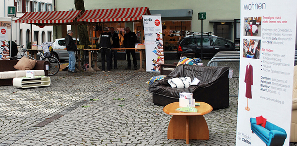 carla stellt wieder Instandgesetzte Möbel in der feldkircher Innenstadt aus. Zwei Roll-ups und eine schwarze Couch stehen am Sparkassenplatz. 