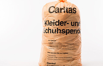 Der orange Caritas Kleidersack. Er hat Platz für zirka 8,5 Kilogramm Kleidung.v