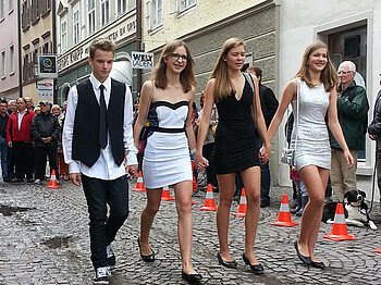 carla Modeschau anlässlich des Reuse Days. Junge Erwachsene, drei Damen und ein Herr, gehen durch die Innenstadt von Feldkich. Alle vier sind dabei modisch gekleidet. 