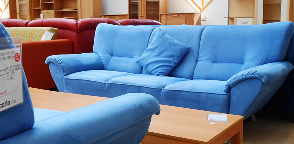Eine blaue Couch steht in einem möbilierten Wohnzimmer. 